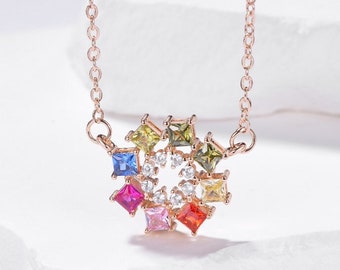 May include: A rose gold necklace with a colorful square-shaped gemstone pendant. The pendant features a circle of smaller white gemstones in the center.