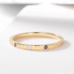 May include: A gold band ring with a crescent moon design and black and white diamonds.