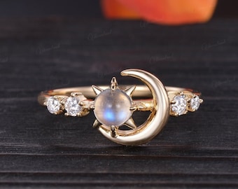 Op de afbeelding: Gouden ring met een halve maan en een ster ontwerp. De ster heeft een ronde maansteen. De ring is bezet met kleine heldere stenen.