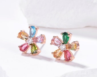 Puede incluir: Un par de pendientes en forma de flor de oro rosa con piedras preciosas de colores. Los pendientes presentan una piedra central transparente rodeada de seis piedras en forma de pera de varios colores, incluyendo rosa, verde, azul y amarillo.