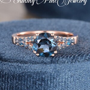 May include: A rose gold engagement ring with a large blue topaz center stone surrounded by smaller blue topaz stones.