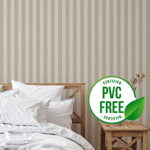 May include: A bedroom scene featuring a bed with white bedding and a wooden headboard. The wall is covered in vertical beige and light gray striped wallpaper. A small wooden side table holds a plant and a sign that reads "CERTIFIED PVC FREE".