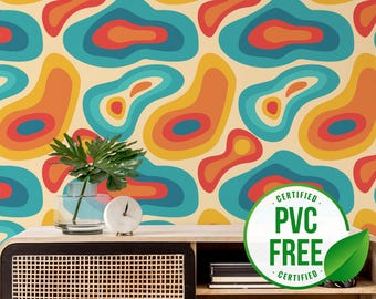 May include: A retro-style wallpaper with a repeating pattern of abstract, layered shapes in shades of orange, yellow, teal, and red against a cream background. A small table holds a plant in a glass vase and a white clock. The image includes a "PVC FREE CERTIFIED" sticker.