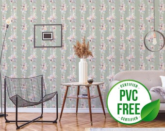 May include: A green and white floral wallpaper with vertical stripes. The wallpaper is shown in a room with a black chair, a wooden table, a white sofa, and a green and white "Certified PVC Free" sticker.