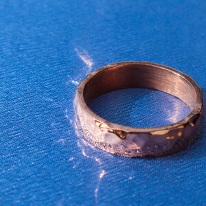 May include: A hammered gold-toned ring with a textured surface.