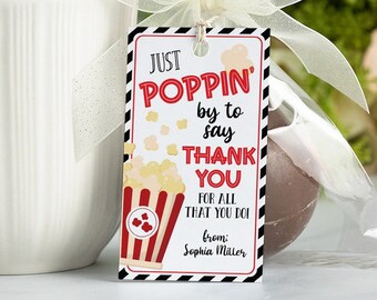 Może przedstawiać: Czerwono-biała etykieta z pudełkiem popcornu z czarno-białymi paskami wokół krawędzi. Etykieta zawiera napis "Just Poppin' by to say Thank You for all that you do!" z imieniem "Sophia Miller" na dole.
