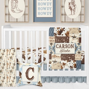 May include: A cowboy-themed nursery set featuring a white cot, bedding, and framed artwork. The bedding has a patchwork design in brown, blue, and white. The wall art includes a cowboy boot, a cowboy on a horse, and the word "HOWDY".