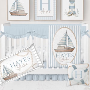 May include: Nautical-themed nursery decor set featuring a crib with blue and white striped bedding, framed sailboat art, and a decorative pillow. The set includes a crib bumper, a crib skirt, and three framed prints with nautical designs.