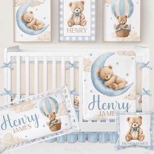 May include: A nursery set with a baby theme, featuring a teddy bear, moon, and hot air balloon. The set includes framed art, a cot, a pillow, and a blanket. The colour scheme is soft blue, beige, and white.