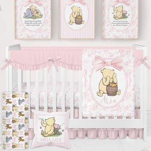 Puede incluir: Un juego de guardería con una cuna blanca y ropa de cama rosa, una manta y un cojín. Tres estampados enmarcados con ilustraciones de Winnie the Pooh cuelgan sobre la cuna. El conjunto tiene una estética suave y femenina.