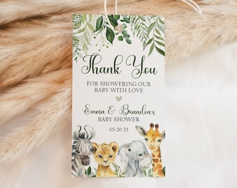 Puede incluir: Gracias por mimar a nuestro bebé con amor, Emma & Brandons Baby Shower 05-20-23. Una etiqueta blanca con follaje verde y un corazón, con una cebra, un león, un elefante y una jirafa.