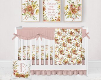 Puede incluir: Una cuna blanca con un juego de ropa de cama de estampado floral rosa. La ropa de cama incluye una sábana bajera, una falda de cuna, una manta y una almohada. La cuna está decorada con tres estampados florales enmarcados, uno de los cuales dice "Nuestra dulce bebé Bethany, eres tan amada".