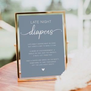 May include: A blue sign with a gold frame that says "Late Night Diapers" in white cursive text. The sign has instructions for guests to write encouraging messages on diapers for the new parents.