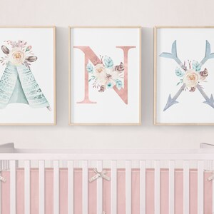 May include: Three framed prints with a boho theme. The first print features a teal teepee with floral accents. The second print features the letter N with floral accents. The third print features two crossed arrows with floral accents.