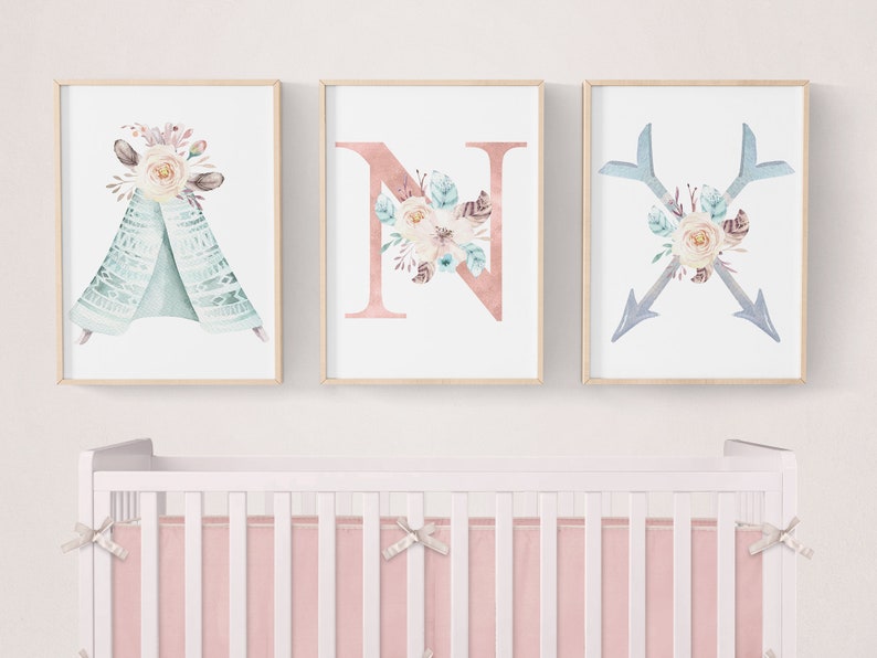 May include: Three framed prints with a boho theme. The first print features a teal teepee with floral accents. The second print features the letter N with floral accents. The third print features two crossed arrows with floral accents.