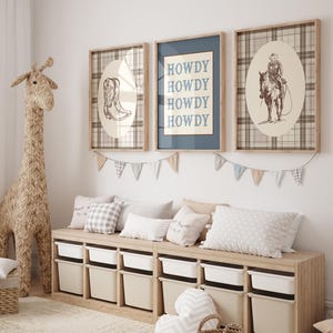 May include: A children's room scene featuring a woven giraffe, framed artwork, and a storage bench. The artwork includes a cowboy boot, the word "HOWDY", and a cowboy on a horse. The bench has white storage bins and is decorated with pillows and a garland.