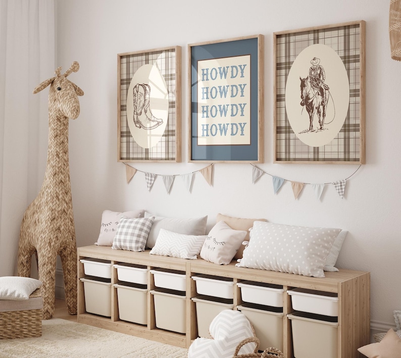 May include: A children's room scene featuring a woven giraffe, framed artwork, and a storage bench. The artwork includes a cowboy boot, the word "HOWDY", and a cowboy on a horse. The bench has white storage bins and is decorated with pillows and a garland.