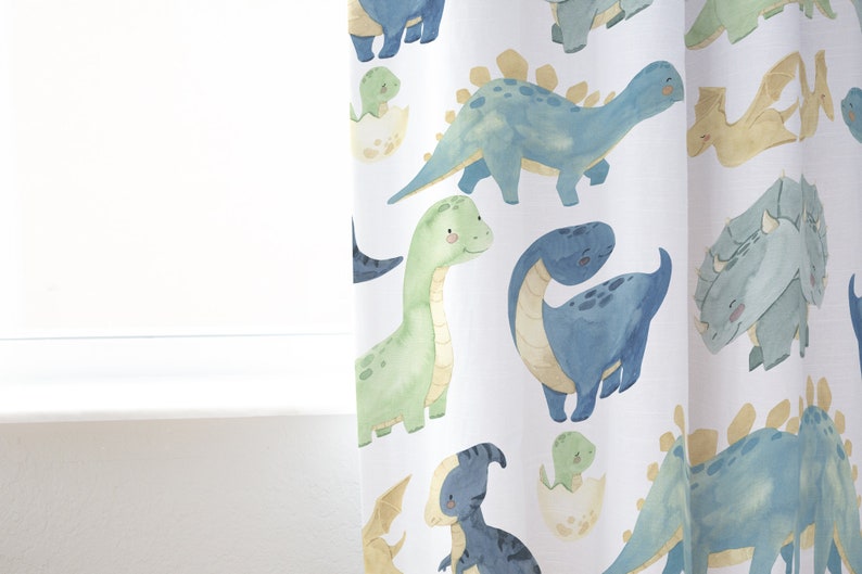 May include: White fabric with a repeating pattern of blue, green, and yellow dinosaurs. The dinosaurs are in various poses, including standing, walking, and sitting. Some dinosaurs are hatching from eggs.