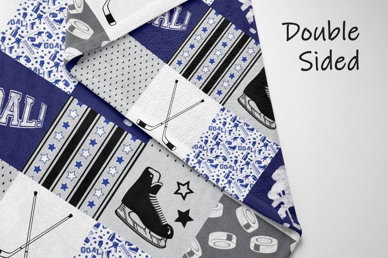 May include: A double-sided fleece blanket with a hockey theme. The blanket features a patchwork design with various hockey-related images, including hockey sticks, skates, pucks, and the word "GOAL!" in a blue and white color scheme.