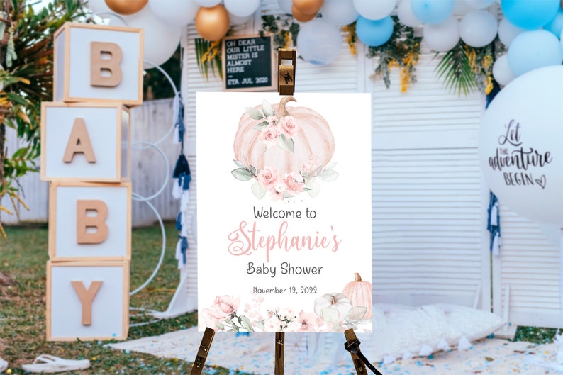May include: A white welcome sign with a watercolor illustration of a pink pumpkin with floral accents. The text reads "Welcome to Stephanie's Baby Shower November 12, 2022".