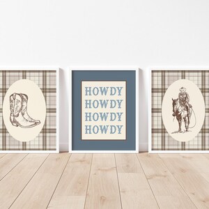 May include: Three framed prints with a Western theme. The prints feature a cowboy boot, the word "HOWDY" repeated, and a cowboy on horseback. Each print has a white frame and a plaid background.