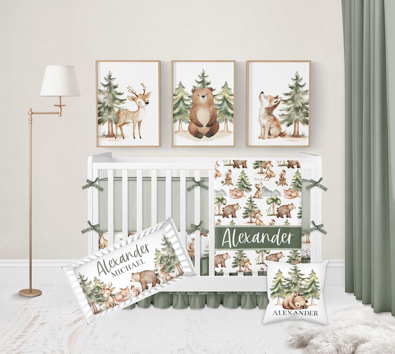 Op de afbeelding: Een kinderkamer set met een witte wieg en groene accenten, met beddengoed met bos thema. De set bevat ingelijste kunstafdrukken van een hert, beer en vos. Een kussen en een decoratieve naambanner zijn ook inbegrepen.