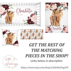 May include: A nursery bedding set with a floral design featuring a Highland cow and calf. The set includes a crib sheet, a pillow, a blanket, and a crib skirt. The crib sheet and blanket are white with a floral pattern in shades of burgundy and pink. The pillow is white with a floral pattern and a Highland cow and calf in the center. The crib skirt is white with a floral pattern and the name "Charlotte" in pink lettering. The set is available in other colors and designs.