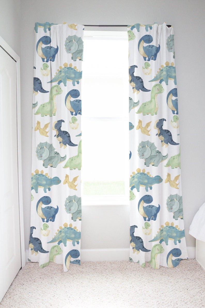 May include: A pair of white curtains with a dinosaur pattern in shades of blue and green. The dinosaurs are illustrated in a watercolor style.