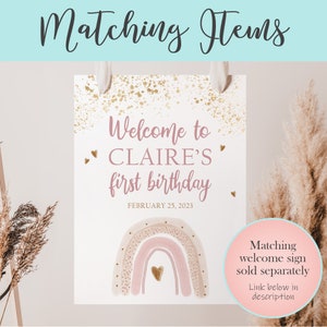 May include: A pink and gold welcome sign with a rainbow and the text "Welcome to Claire's first birthday, February 25, 2023".