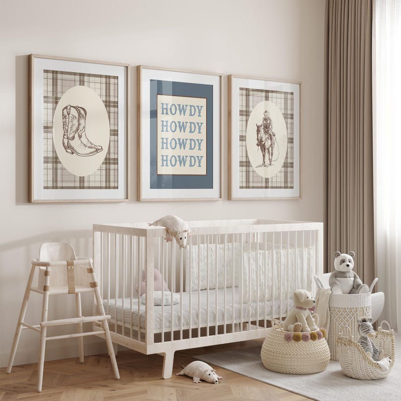 May include: A nursery scene with three framed prints featuring cowboy-themed illustrations and the word "HOWDY." A white crib, high chair, and baskets filled with stuffed animals complete the decor. The color palette is neutral with beige, white, and brown tones.