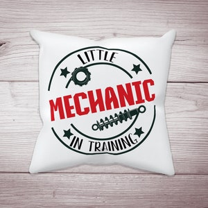 May include: White pillow with a black and red circle design. The circle says "Little Mechanic in Training" with a gear and a spring inside.