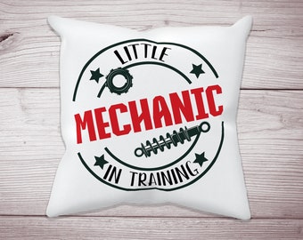 May include: White pillow with a black and red circle design. The circle says "Little Mechanic in Training" with a gear and a spring inside.