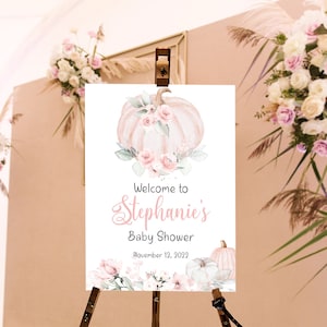 May include: Welcome to Stephanie's Baby Shower sign with a watercolor illustration of a pink and white pumpkin with flowers and greenery. The sign also includes the date November 12, 2023.