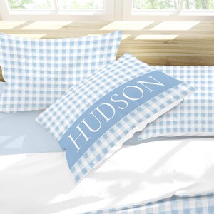 May include: Two blue and white gingham pillowcases with the name "HUDSON" embroidered on one pillowcase.