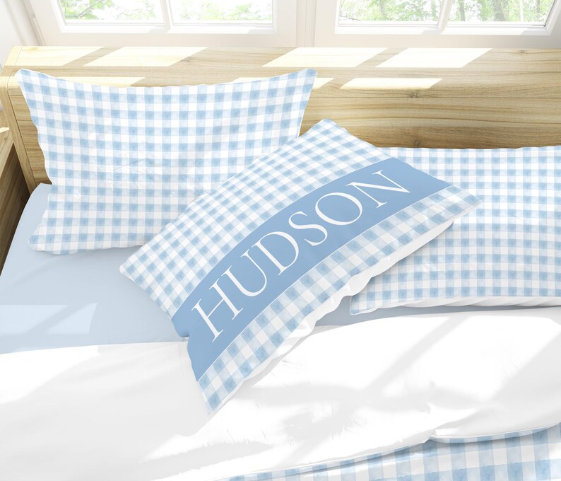 May include: Two blue and white gingham pillowcases with the name "HUDSON" embroidered on one pillowcase.