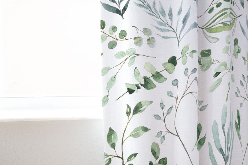 May include: White curtain panel with a watercolor botanical design. The pattern features green and blue-green leaves and branches. The curtain is near a white window frame.