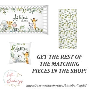 May include: A white crib sheet with a green leafy pattern and a watercolor illustration of a giraffe, elephant, and lion. The sheet is personalized with the name "Ashton Blake".