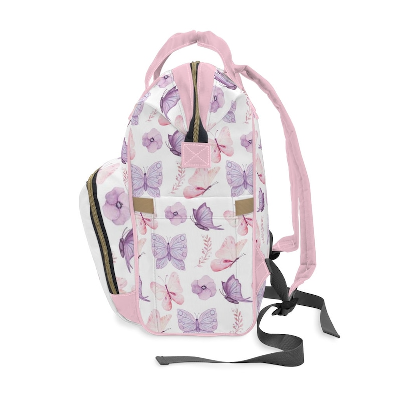 May include: Pink backpack with a white background and a pattern of purple butterflies and pink flowers.