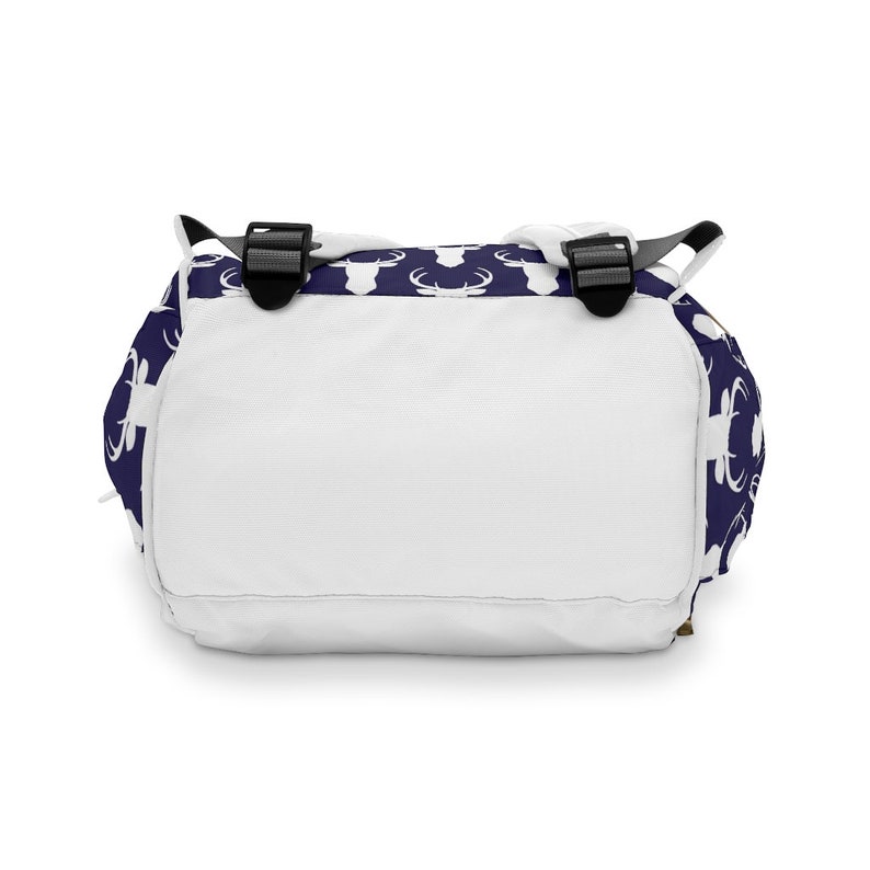 May include: A white backpack with adjustable straps. The backpack has a navy blue background with a white deer silhouette pattern.
