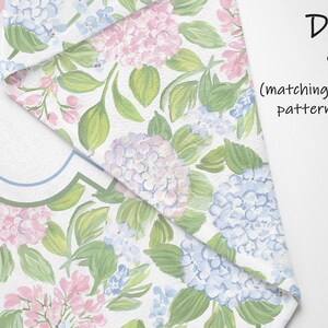 Puede incluir: Un tejido con un estampado floral de flores de hortensia rosas y azules con hojas verdes sobre un fondo blanco. La tela est&aacute; doblada para mostrar un patr&oacute;n de hortensias a juego en el reverso. El texto en la imagen dice Double Sided.