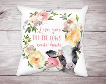 May include: White pillow with a floral wreath and a black and white calf with pink flowers in its hair. The text reads "Love you till the cows come home."