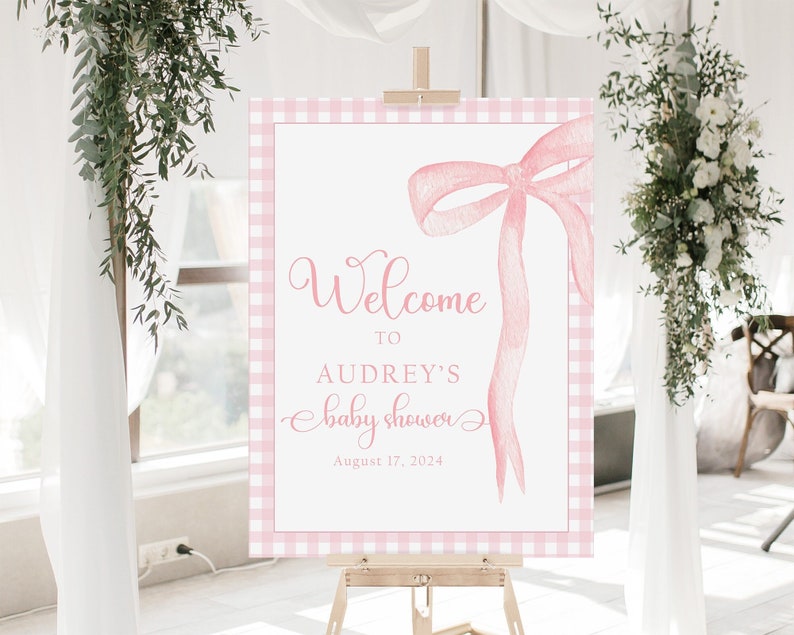 May include: Pink and white gingham welcome sign with a pink watercolor bow and the text "Welcome to Audrey's Baby Shower August 17, 2024".