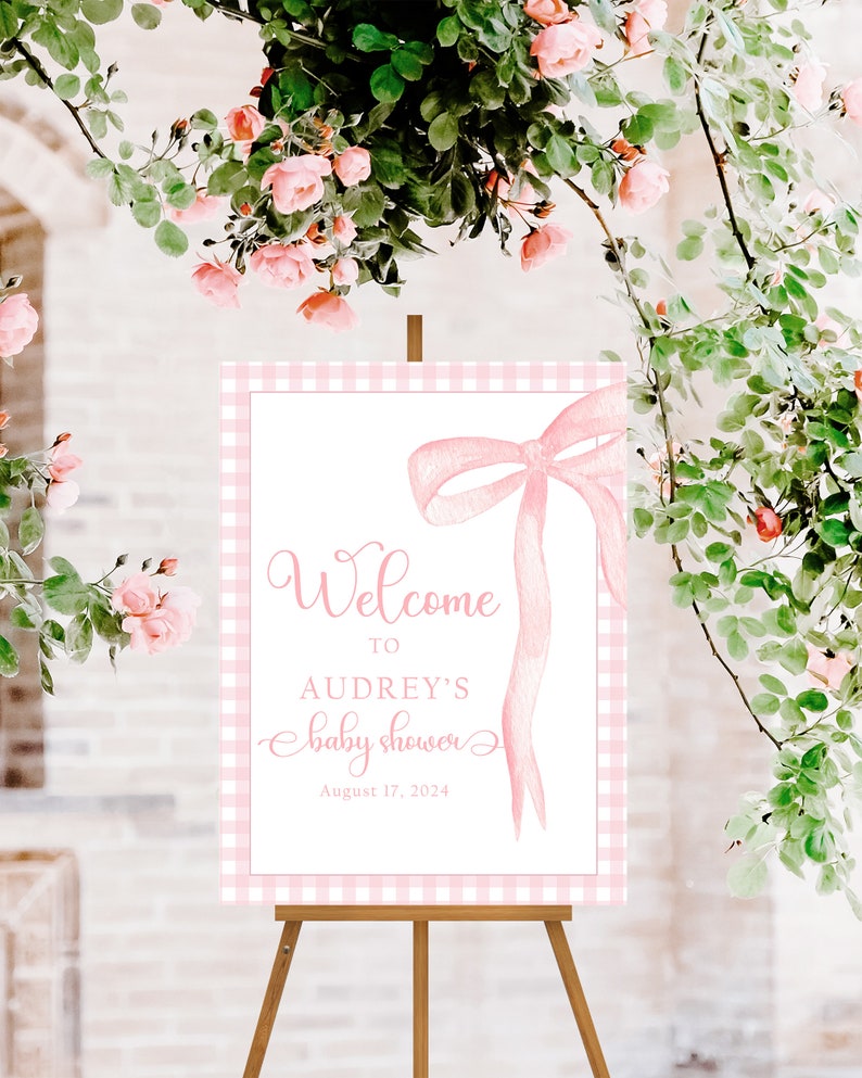 May include: Pink and white gingham welcome sign with a pink bow and the text "Welcome to Audrey's Baby Shower August 17, 2024".