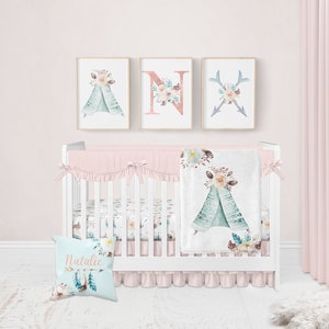 May include: A white crib with a pink and white floral crib bedding set. The bedding features a teepee design with watercolor flowers and feathers. The crib also has a personalized pillow with the name "Natalie" and a floral arrow design.