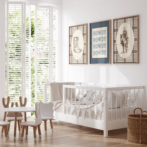 May include: A bright, airy nursery with a white crib, a small table and chairs, and three framed prints. The prints feature cowboy-themed illustrations and the word "HOWDY". A woven basket sits on the floor.