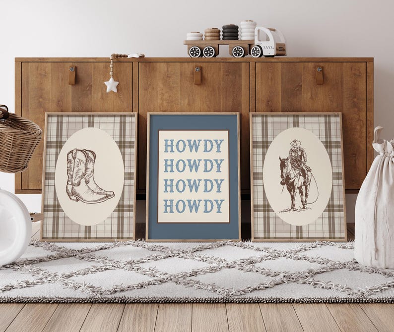 May include: Three framed prints with a Western theme. One print features a cowboy boot, another a cowboy on a horse, and the third says "HOWDY" in blue letters. The prints are on a plaid background.