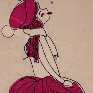以下が含まれることがあります： ピンクの帽子、白いセーター、ピンクのスカートを着た女の子の刺繍イラスト。彼女は頭を後ろに傾け、口を開けてひざまずいています。