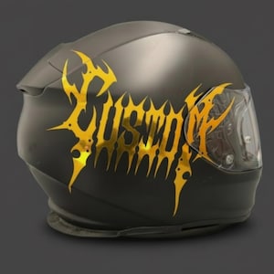 May include: A matte black motorcycle helmet with a gold graphic design that reads "USURPER". The helmet has a clear visor and is designed for safety and protection. The graphic is a bold, stylized font.