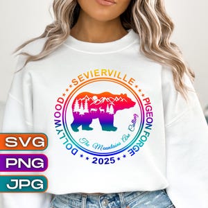 May include: White sweatshirt featuring a colorful graphic of a bear, mountains, and trees inside a circle. Text includes "Sevierville", "Pigeon Forge", "Dollywood", "The Mountains Are Calling", and "2025". The sweatshirt also has SVG, PNG, and JPG icons.