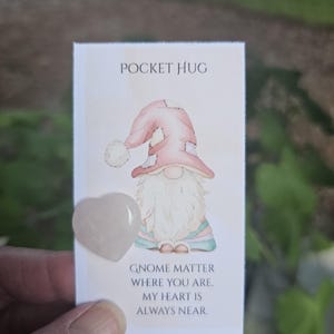 May include: A Pocket Hug card with a watercolor illustration of a gnome wearing a pink hat and a heart-shaped rose quartz stone. The card reads "Pocket Hug" and "Gnome matter where you are, my heart is always near."